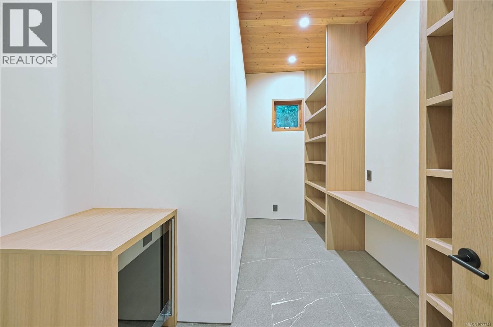Storage room with pale wood built-in shelves, tiled floor, and a wood-plank ceiling.