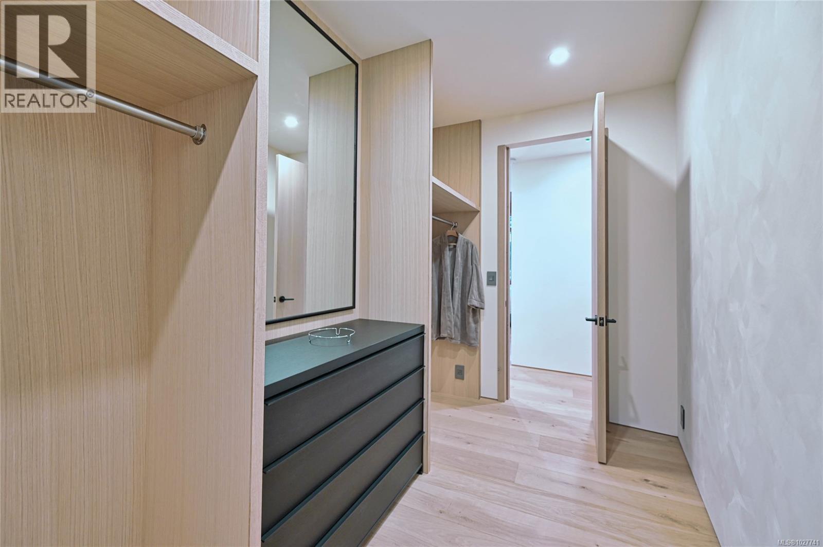 Dressing area with light wood built-ins, dark drawers, a full-length mirror, and hanging space.