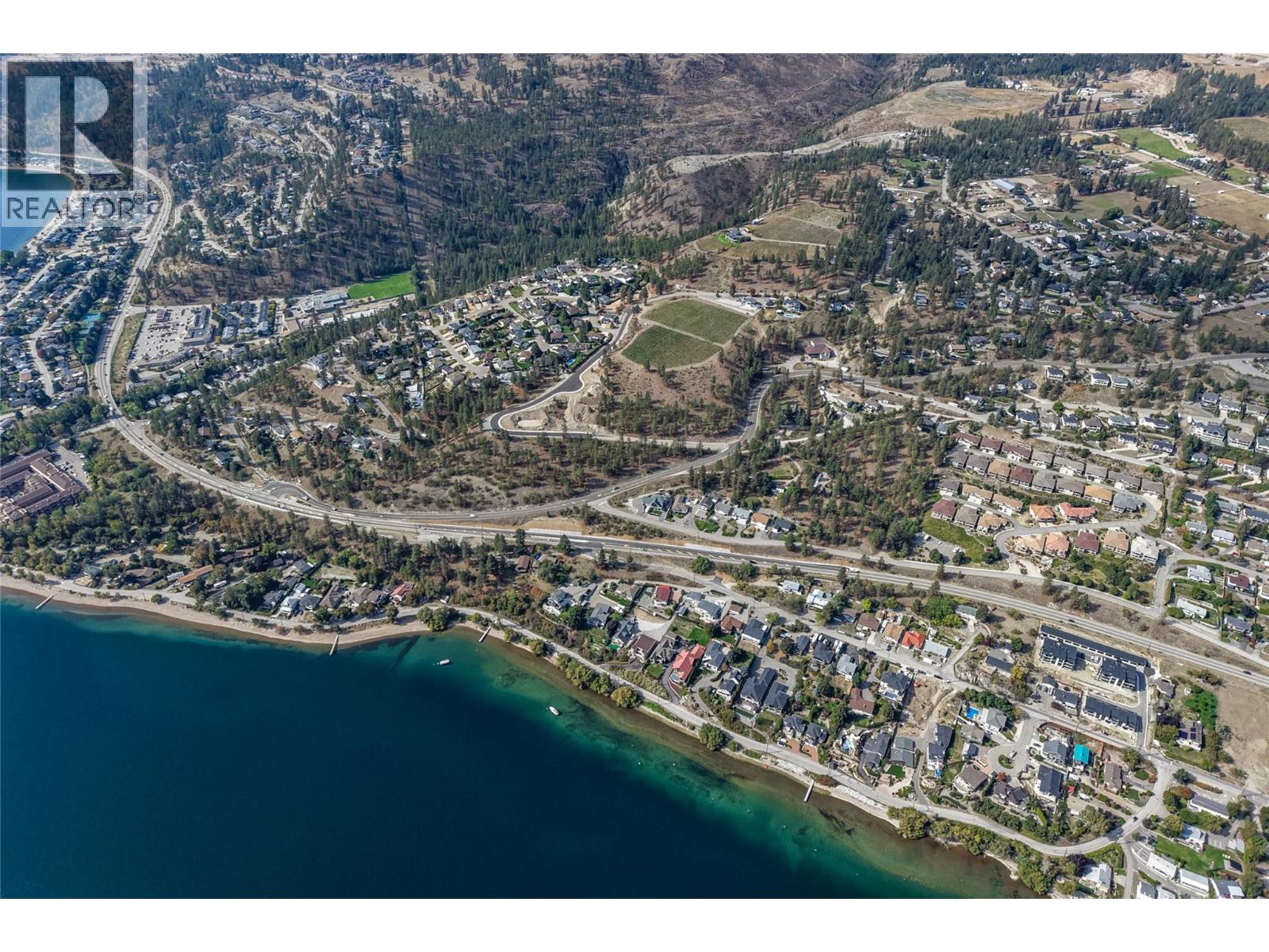 Aerial view of a lakeside neighborhood with wooded hills and a curving shoreline.