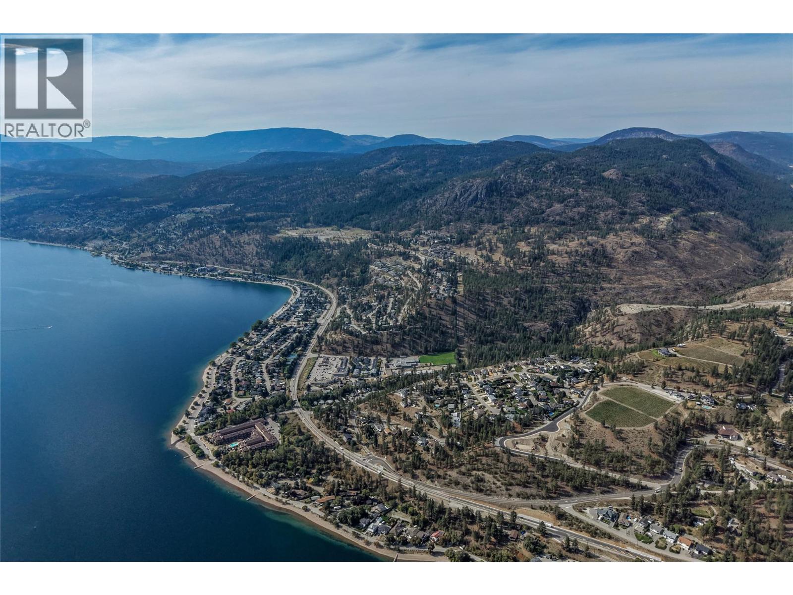 Aerial view of a lakeside community beneath rugged, forested mountains.