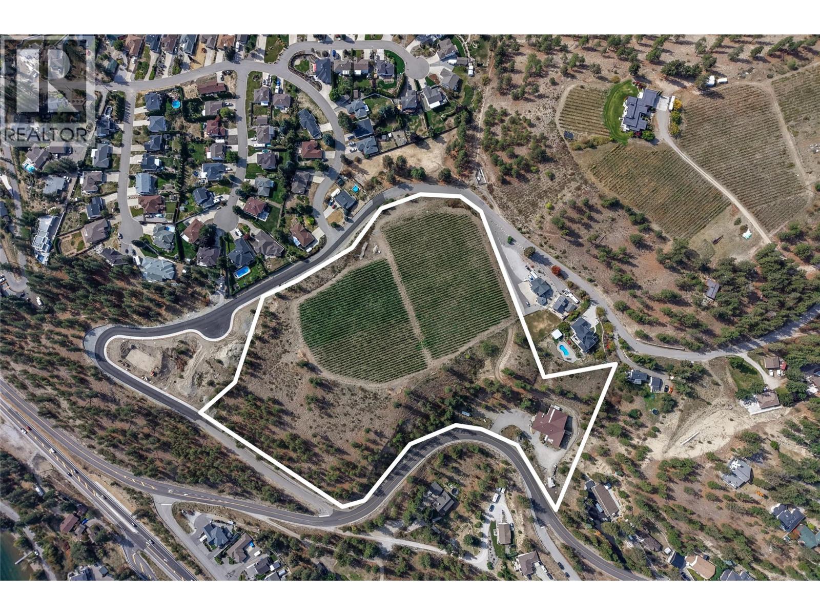 Aerial view of outlined property with vineyard rows, open land, and nearby homes.