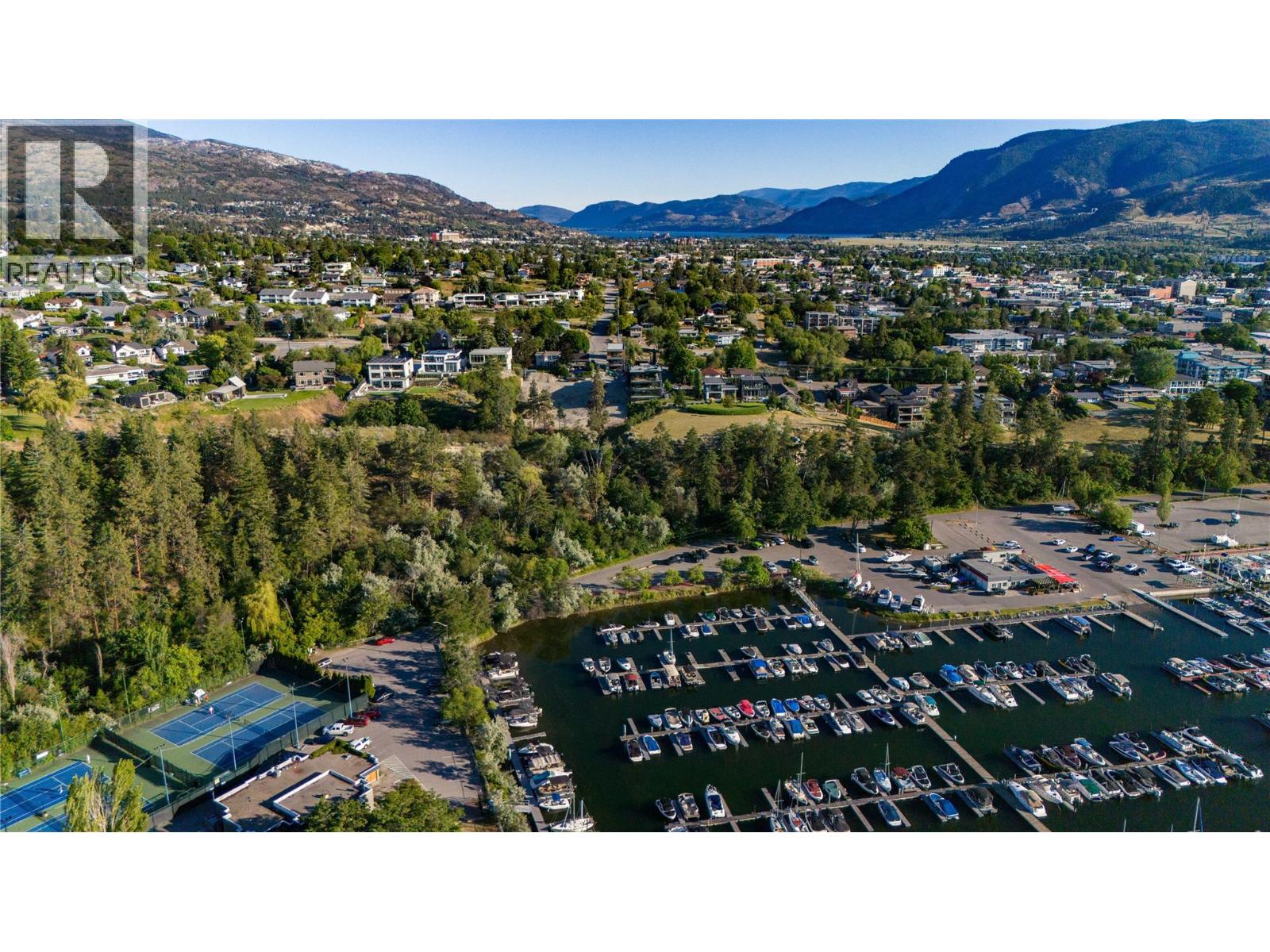 Aerial panorama of a marina, tree-lined neighborhoods, and mountains surrounding a lakeside town.