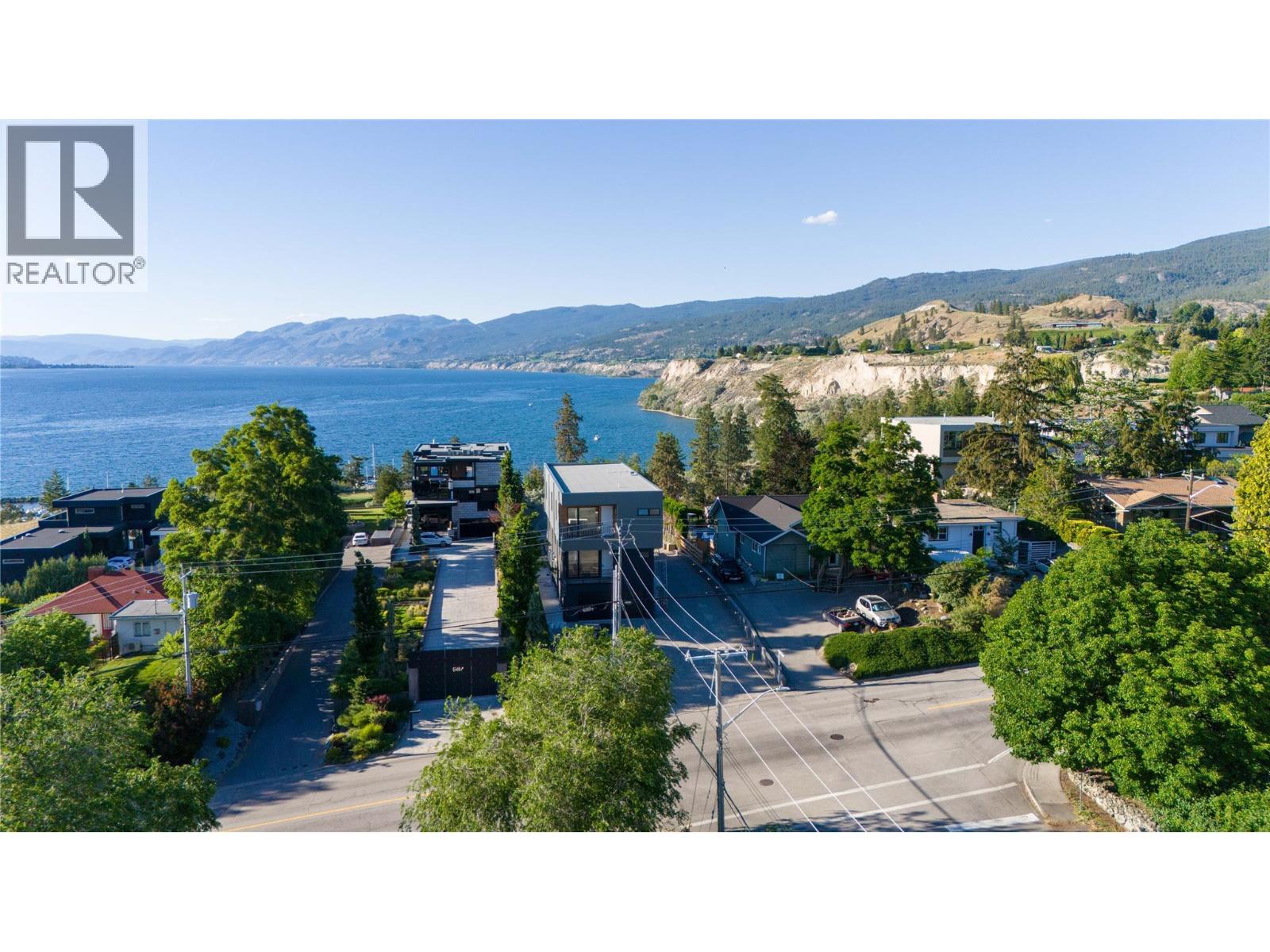 Aerial view of homes above the lake, with mountain ridges and shoreline.