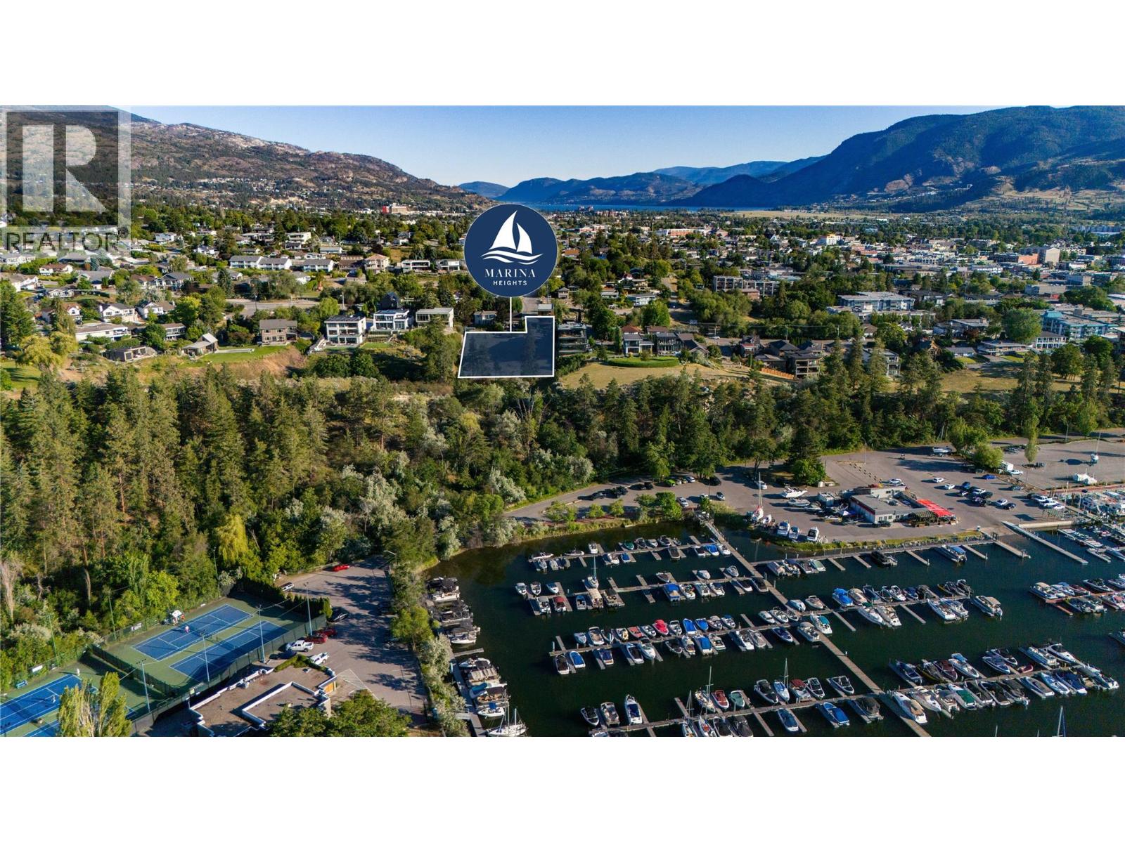 Aerial view of a highlighted Marina Heights lot above a marina, with mountains beyond.
