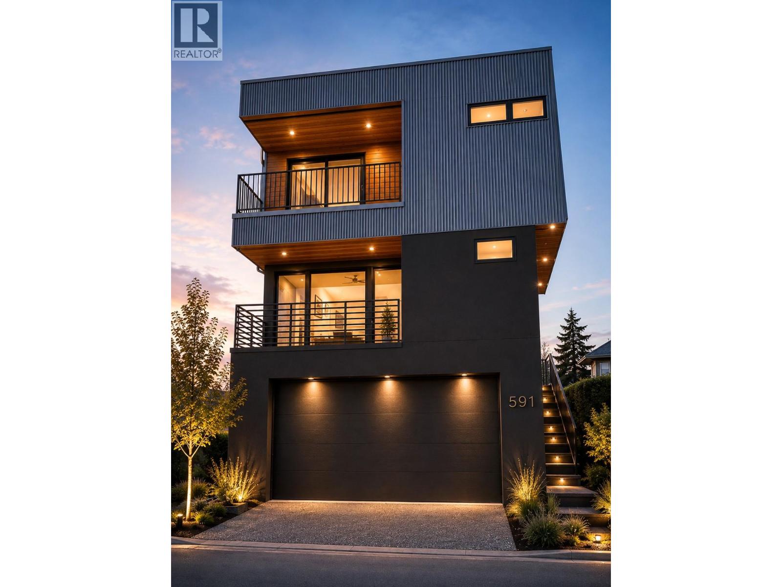 Modern multistory home with balconies, a wide garage, and landscaped entrance illuminated at dusk.