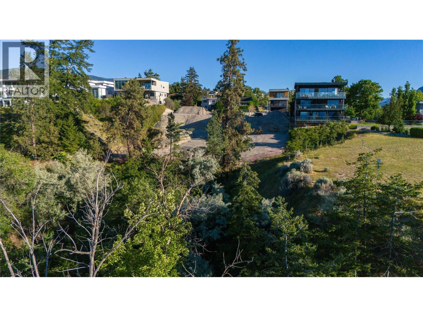 Elevated view of a cleared hillside lot among modern homes and trees.