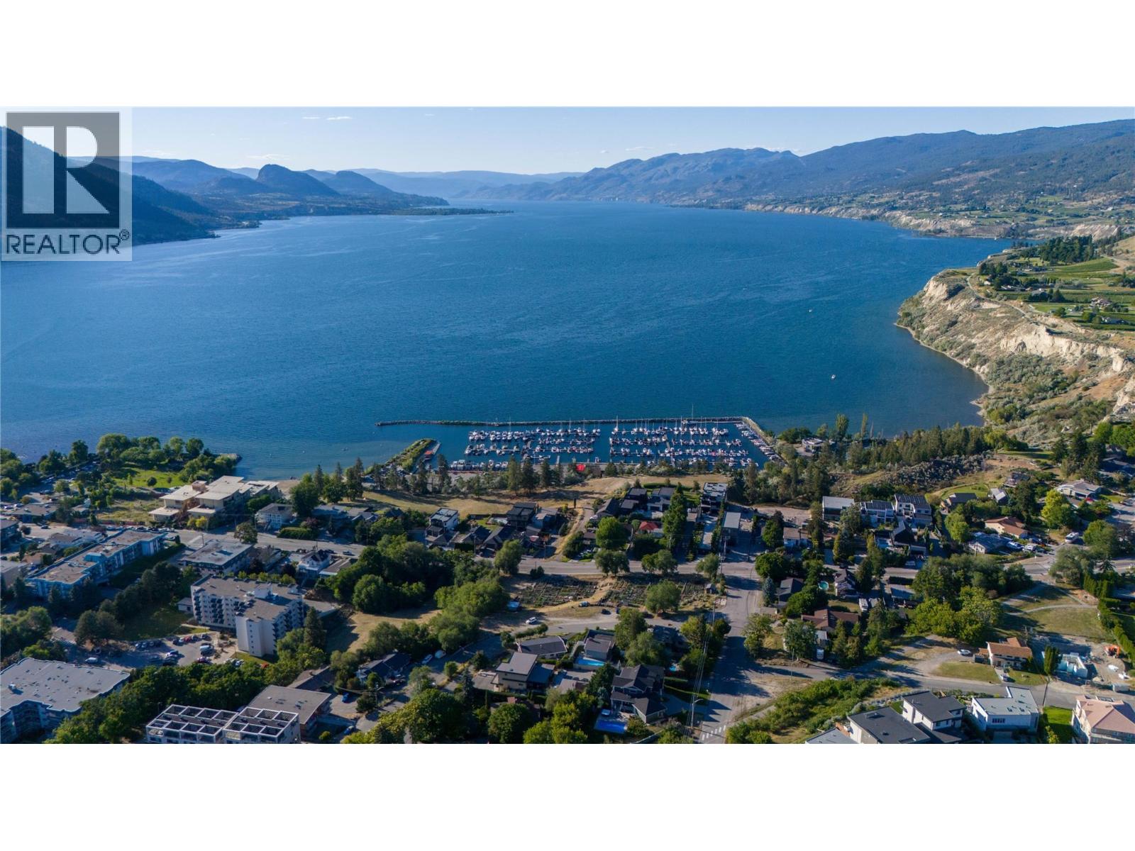 Aerial view of a lakeside town and marina, with mountains across the water.