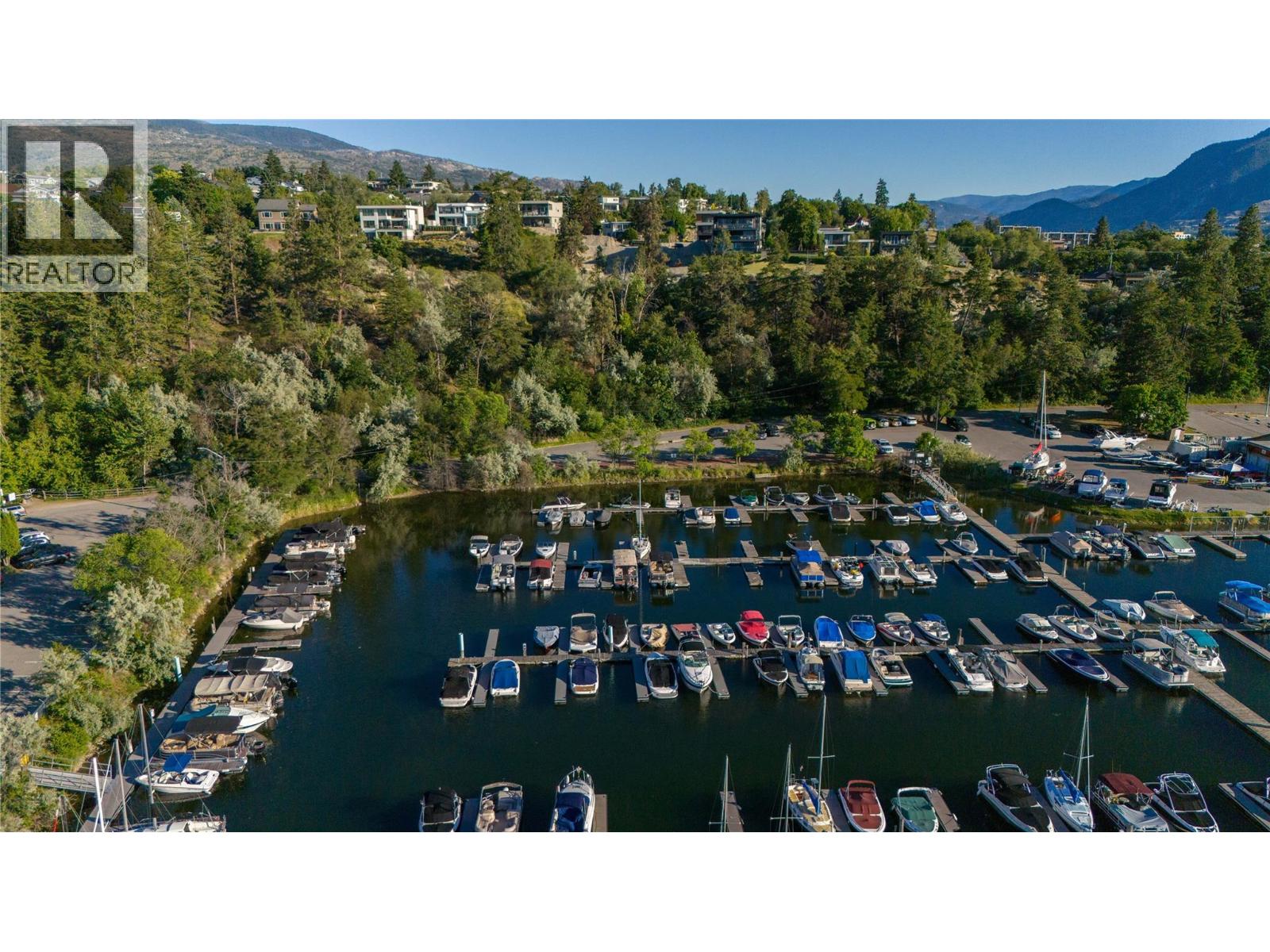 Aerial view of a marina with boats and docks below wooded hills and homes.