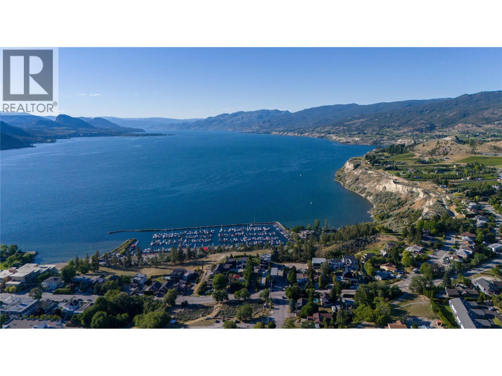 Aerial view of a lake and mountain shoreline, with a marina and homes in the foreground.