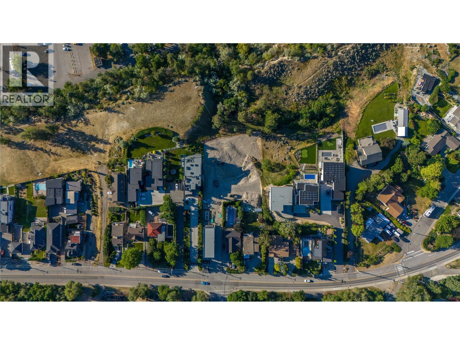 Aerial view of a vacant graded lot between homes and open land.