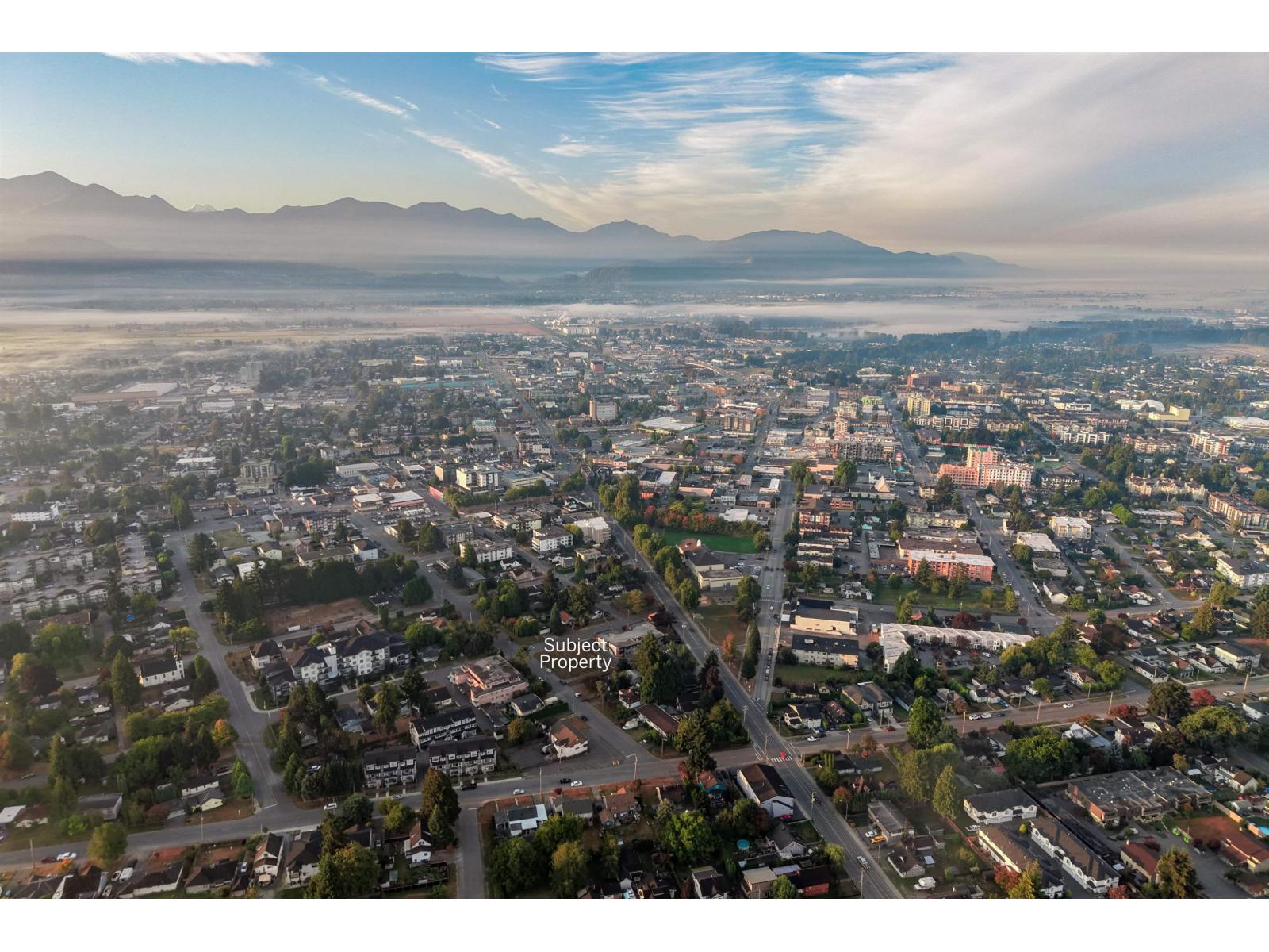 Aerial view of the property’s neighborhood, with city blocks and mountains beyond.