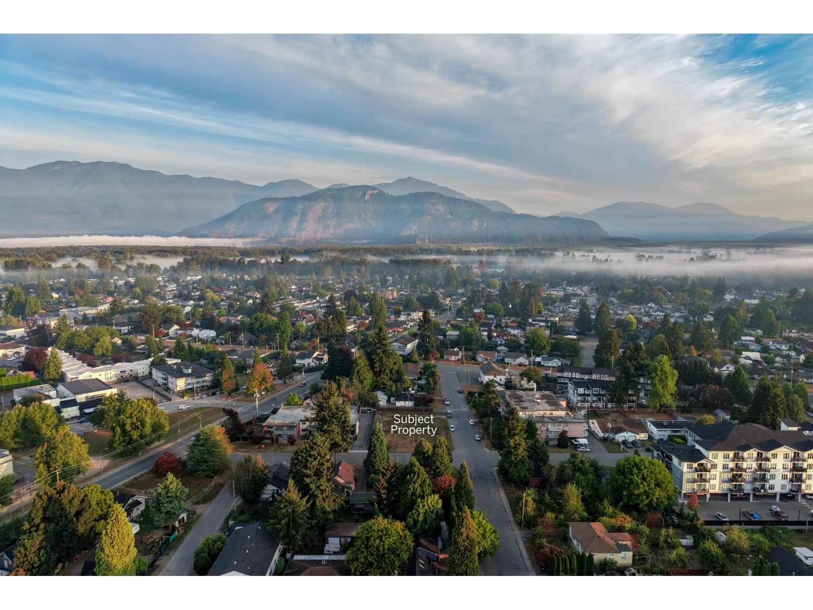 Aerial view of a Chilliwack neighborhood with misty mountains behind it; the subject property is marked.
