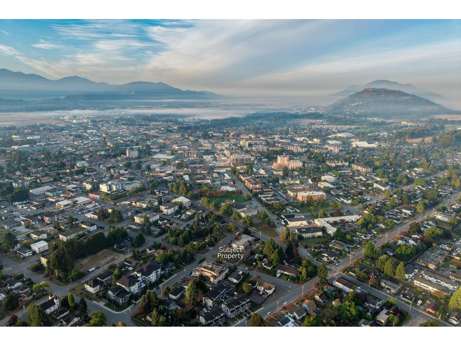 Aerial view of Chilliwack’s neighborhoods and commercial district, with misty mountains on the horizon.