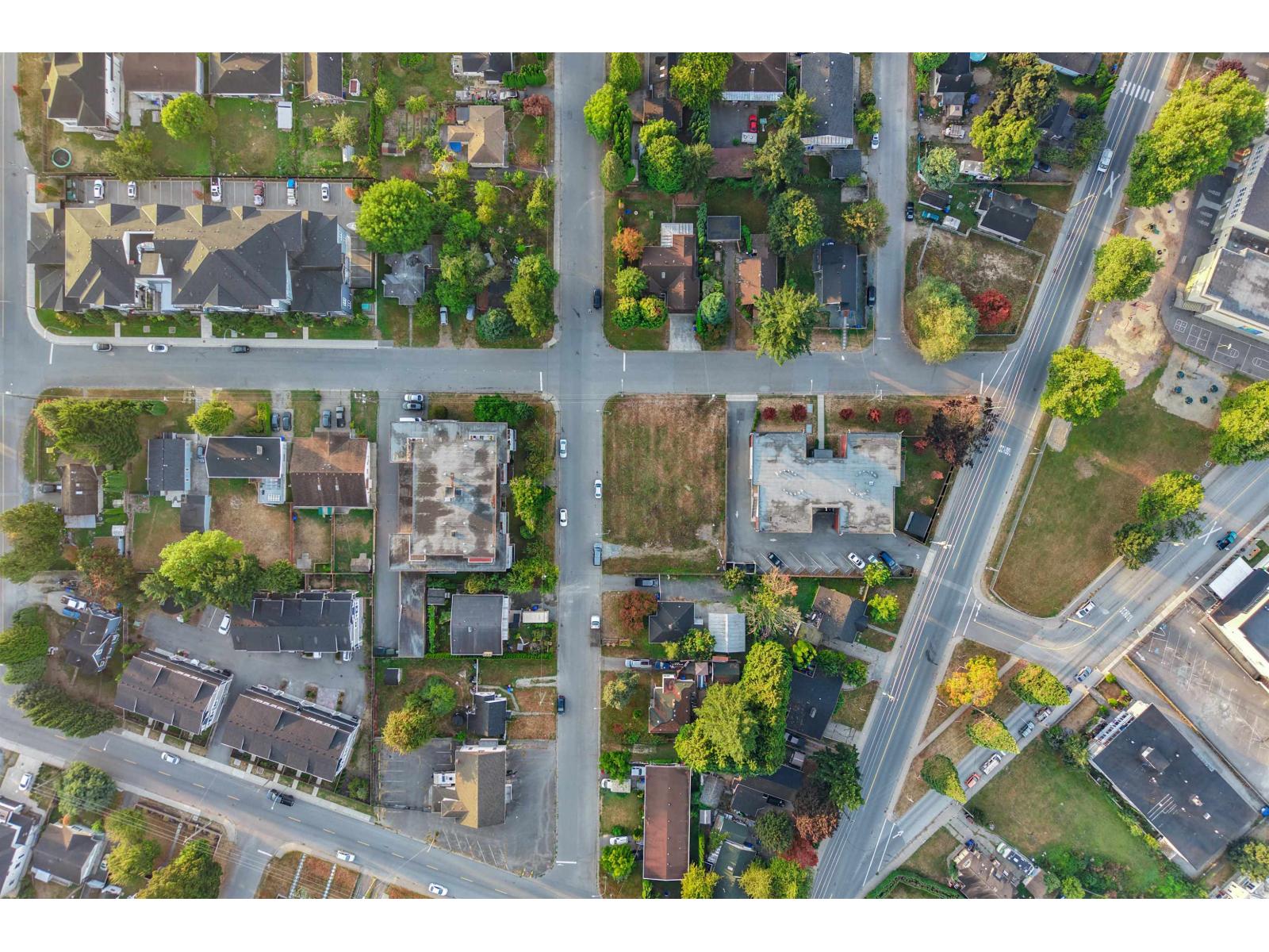 Aerial view of a neighborhood with homes, trees, and a major road.