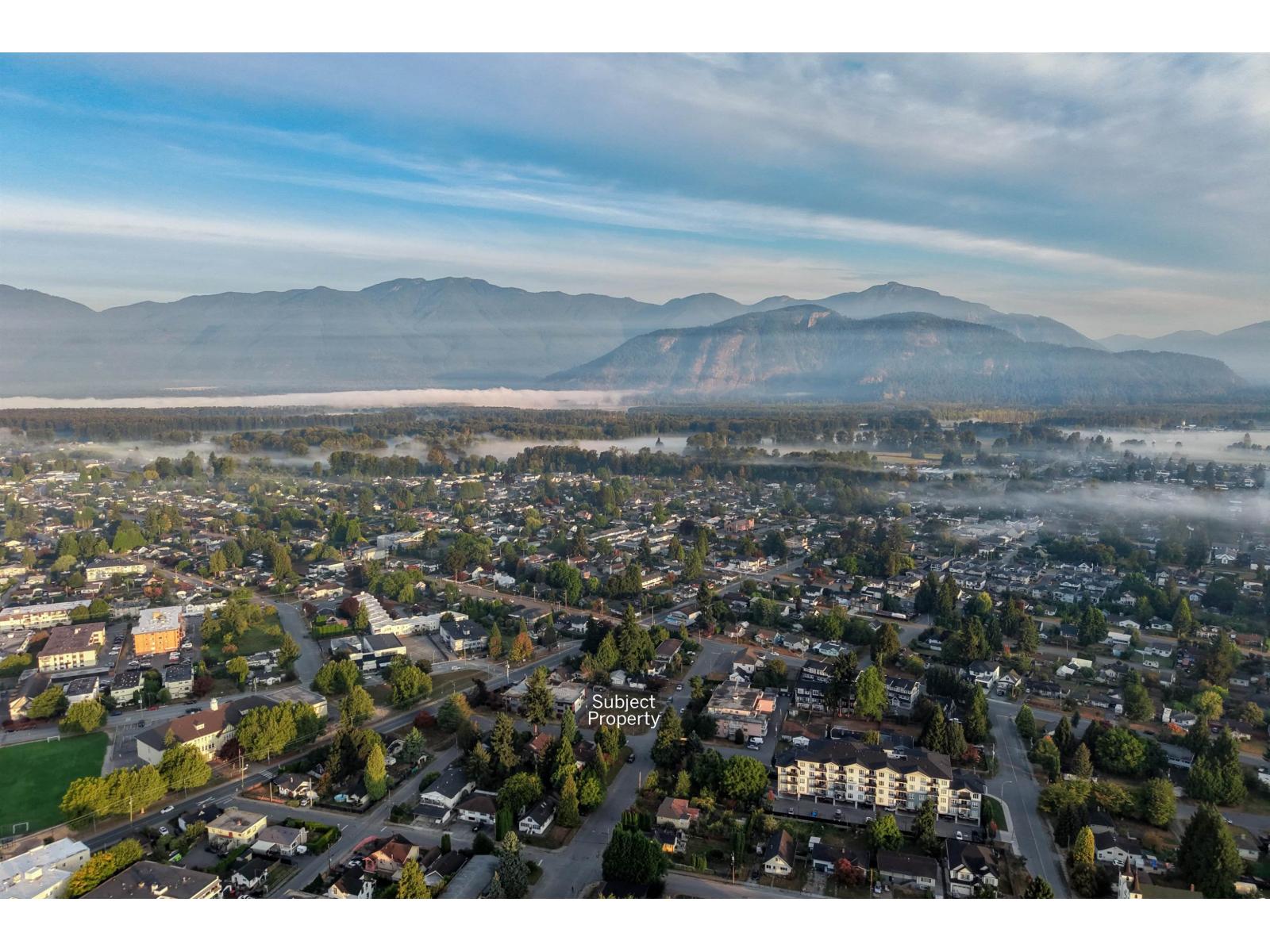 Aerial view of the subject property area, with misty residential streets and mountains beyond.