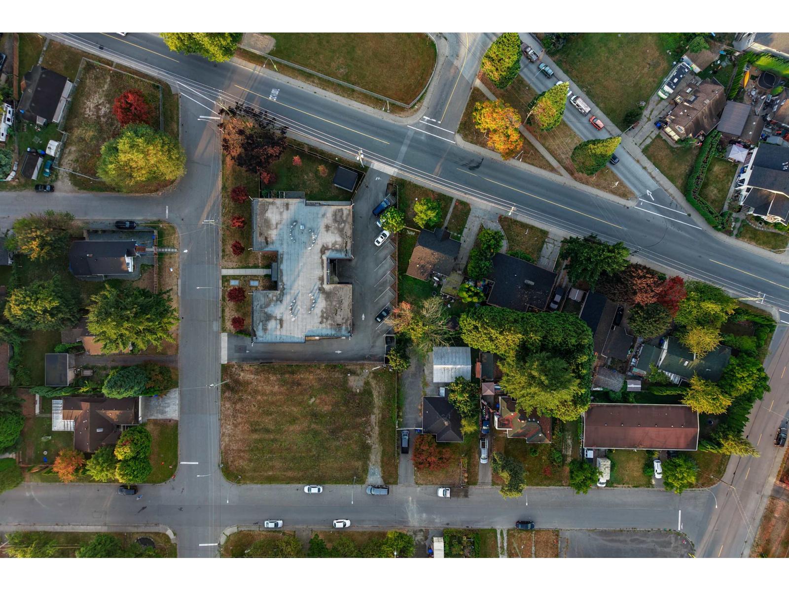 Aerial view of a flat-roof building among homes and tree-lined streets.