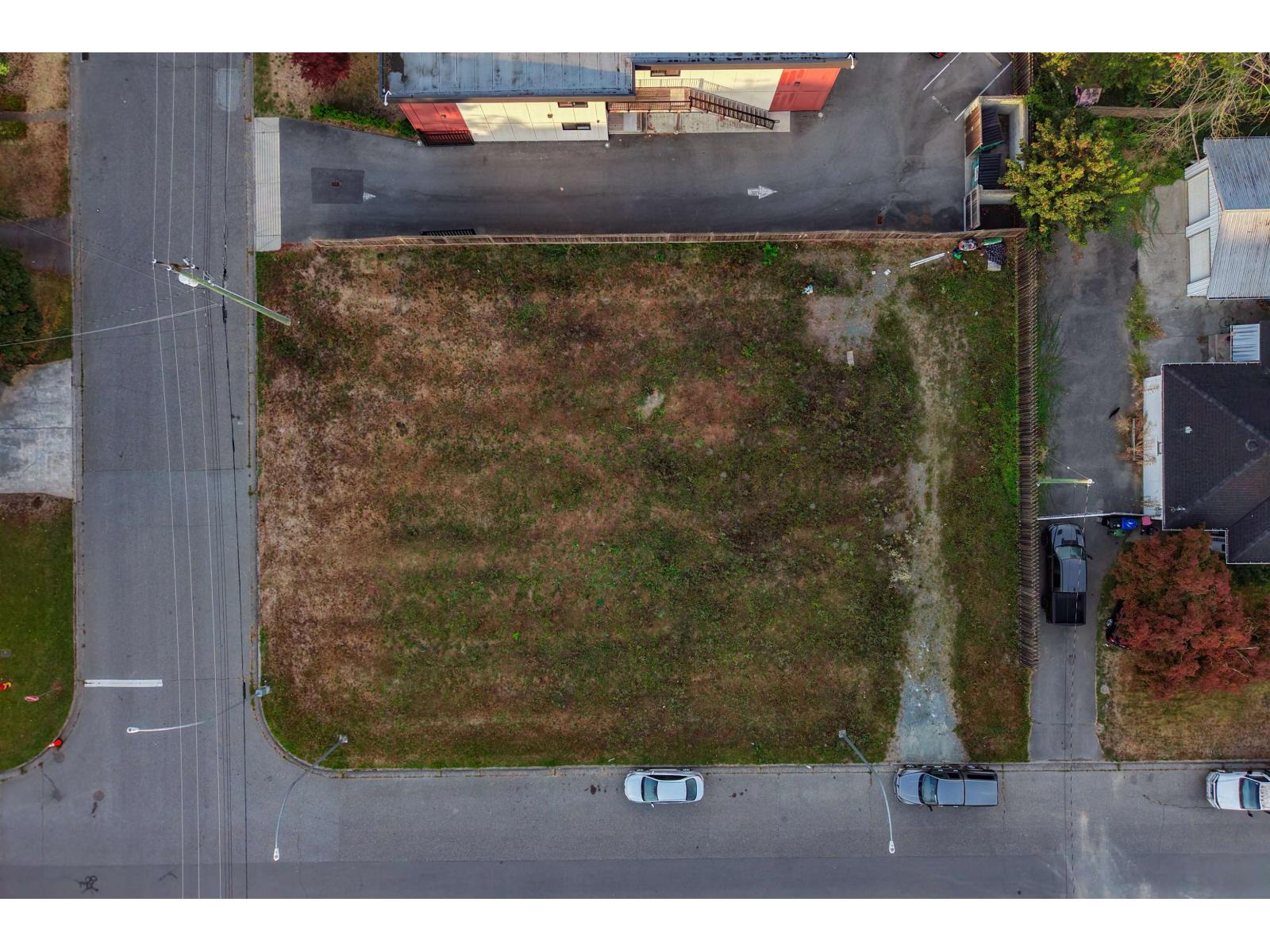 Aerial view of a vacant grassy lot bordered by streets and neighboring homes.