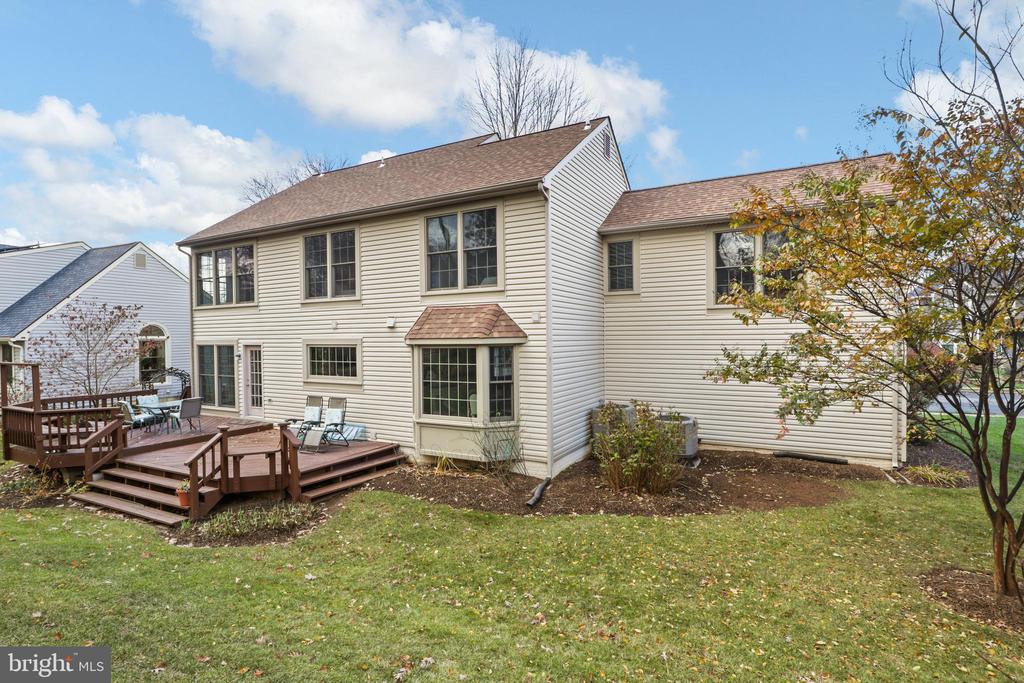 Rear of a beige two-story home with large windows and a raised wooden deck.