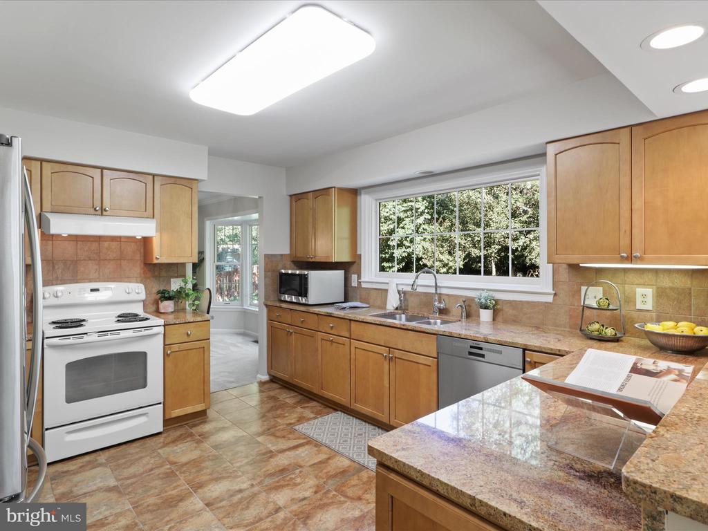Kitchen with warm wood cabinetry, granite counters, and a large window above the sink.