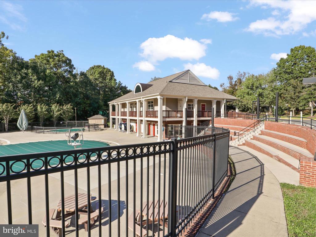 Community pool and clubhouse beside curved brick amphitheater seating.