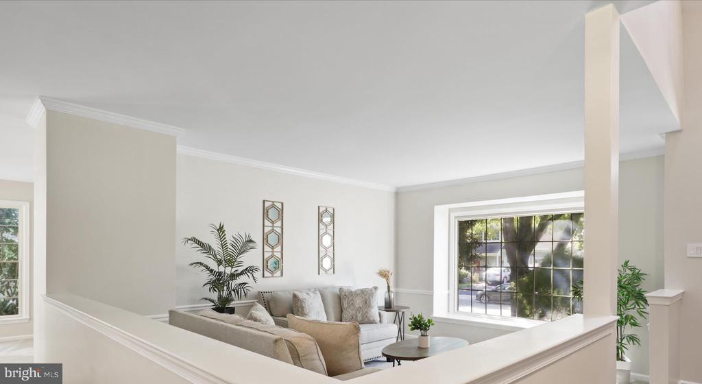 Staged living room with a neutral sofa, half-height railing, and large divided-pane window.