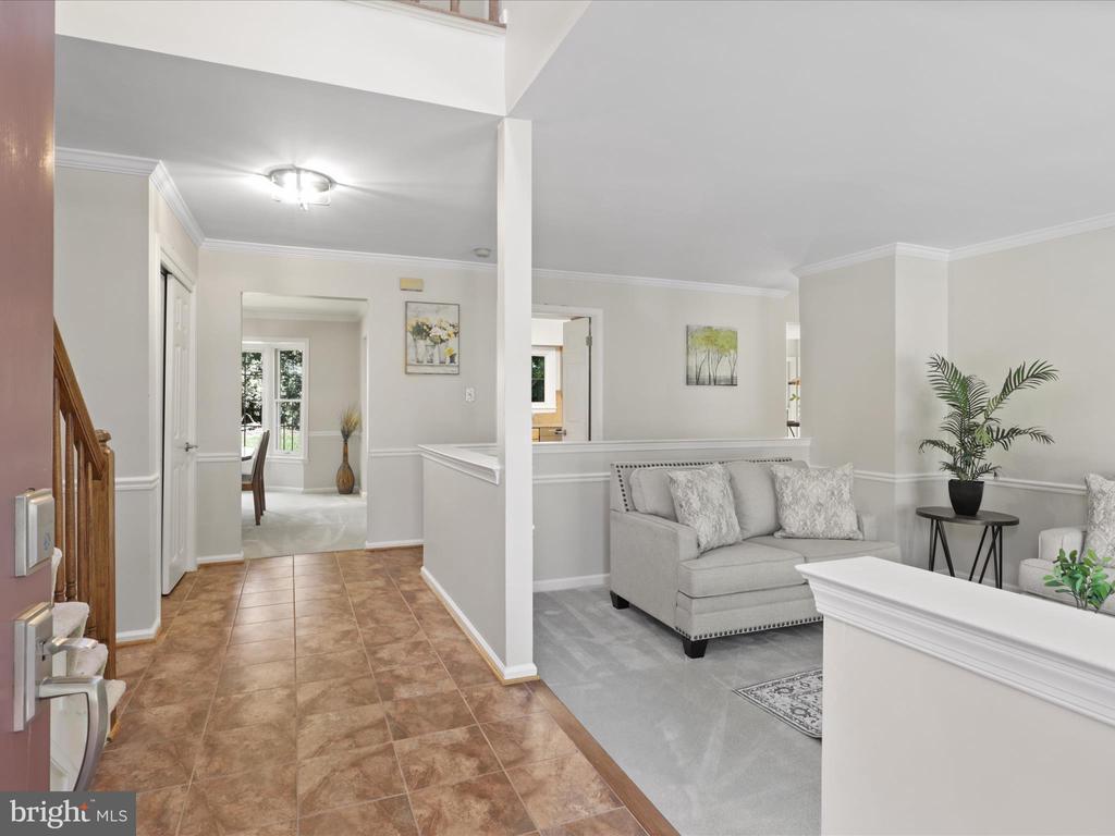 Open entryway leading into a living room with a gray sofa and tiled foyer floor.