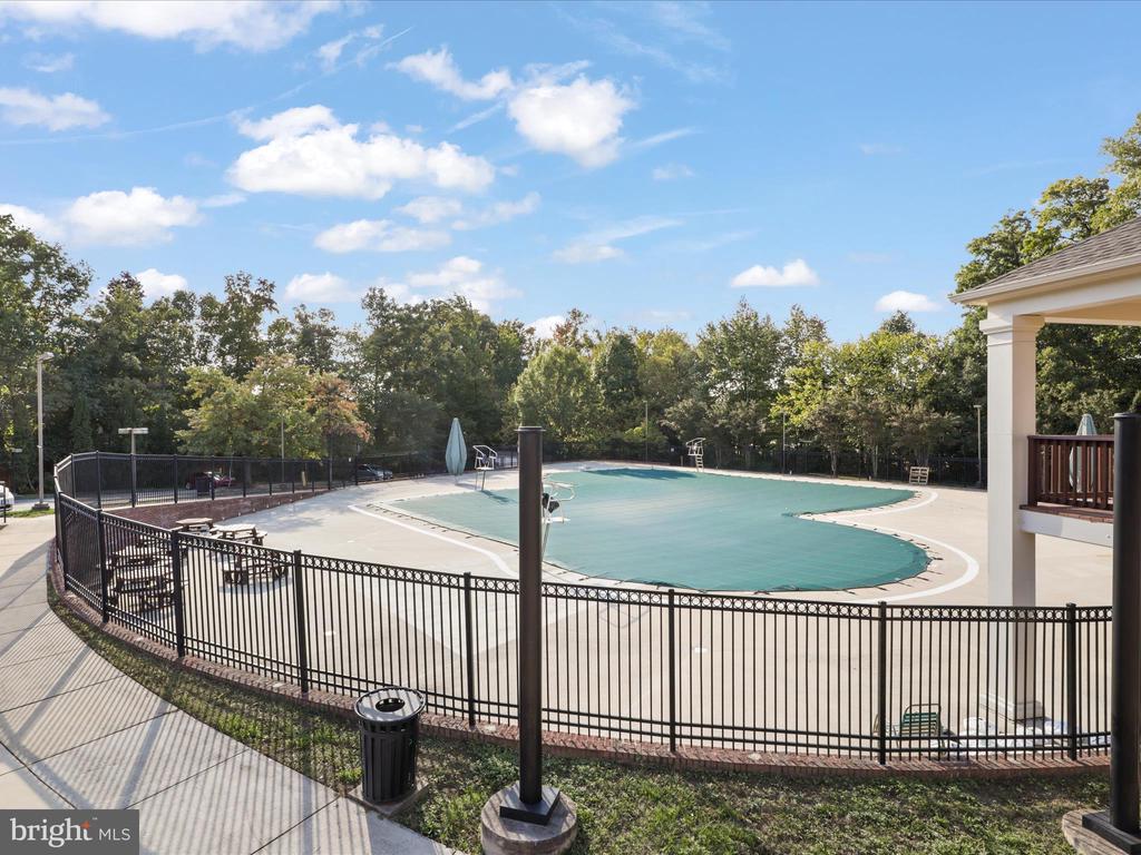 Outdoor swimming pool with a turquoise cover, fenced deck, and surrounding trees.