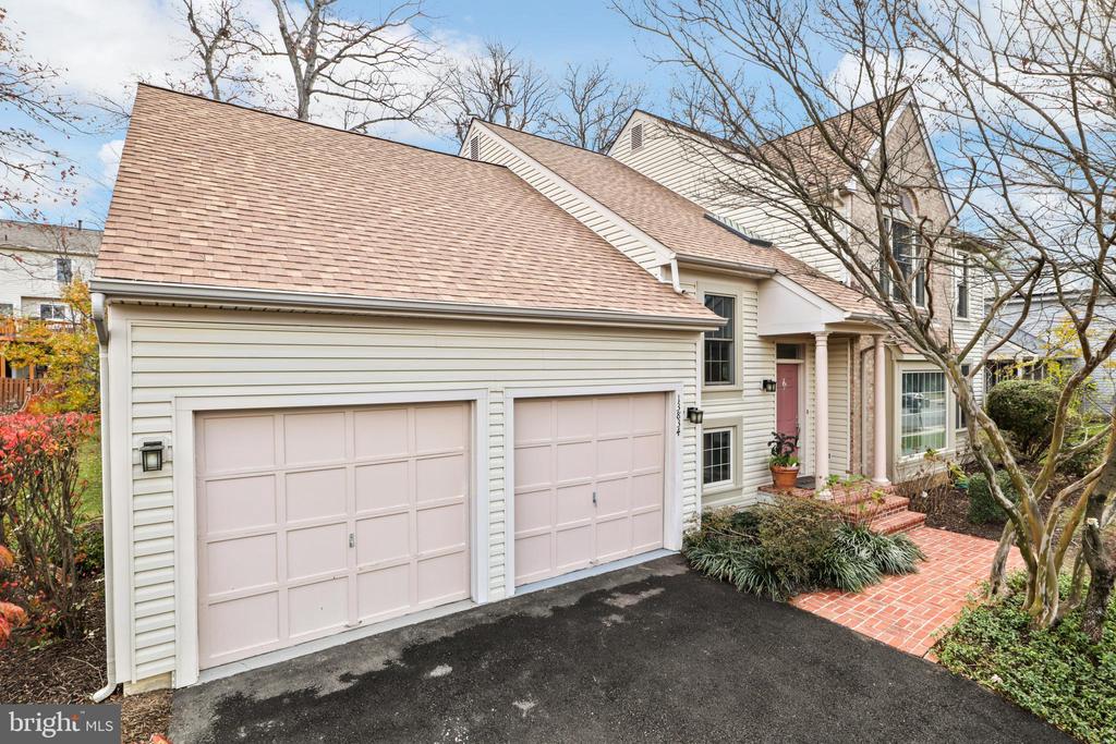 Home exterior with two pale pink garage doors and a brick walkway to the entrance.
