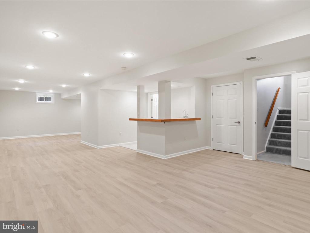 Vacant open interior with light flooring, a wood-edged counter, and stairs.