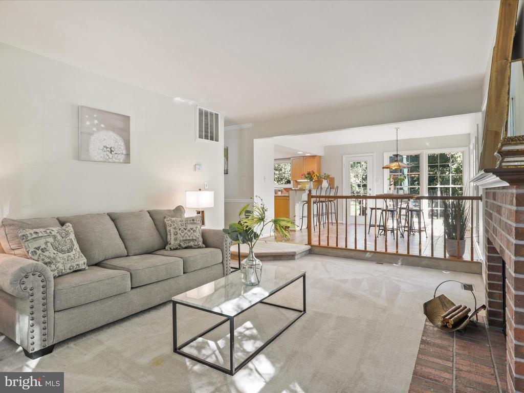 Living room with gray sofa, brick fireplace, and open view to kitchen and dining area.