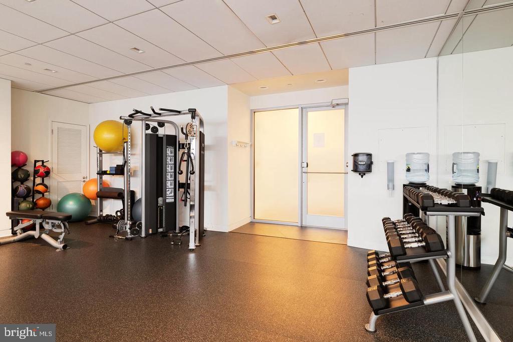 Building fitness room with a cable machine, dumbbell racks, exercise balls, and a mirrored wall.