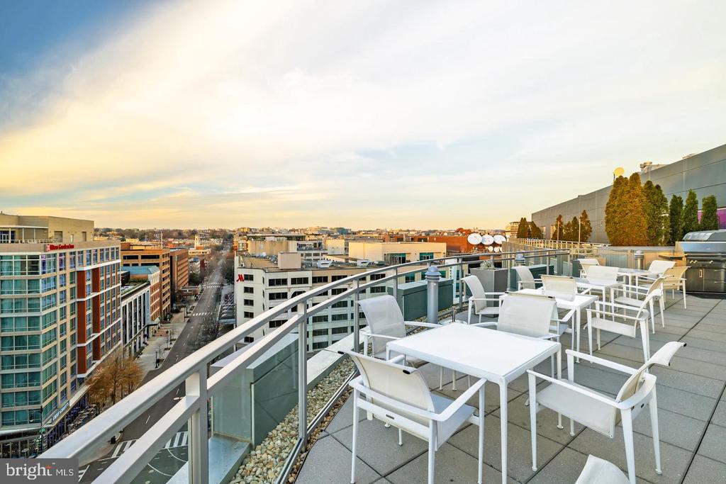 Rooftop terrace with white patio furniture and a broad city skyline view.