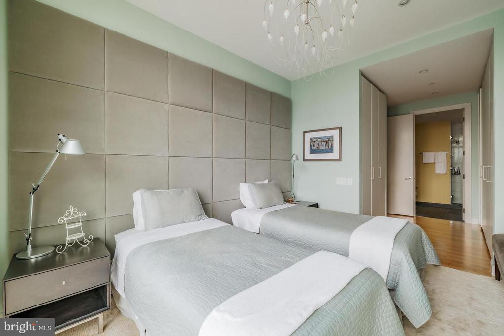 Bedroom with two white-and-gray beds and a floor-to-ceiling padded wall.