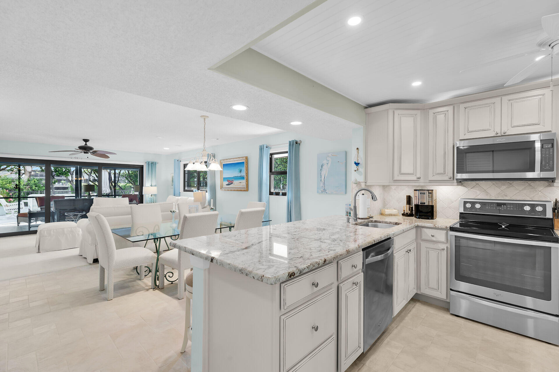 Open-plan kitchen and living area with a large stone island and sliding glass doors to a patio.
