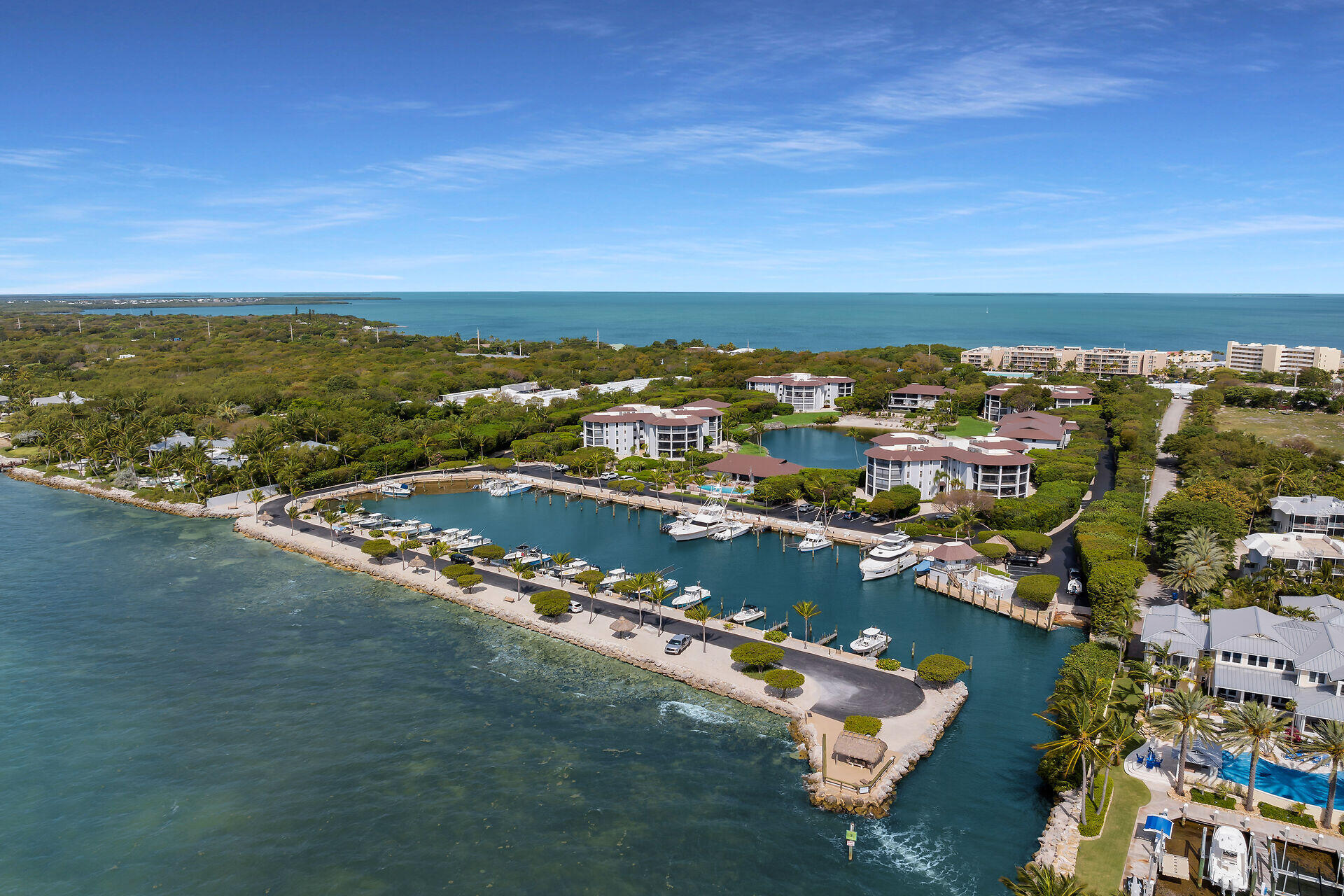 Waterfront condominium community with a marina and boats beside the open ocean.