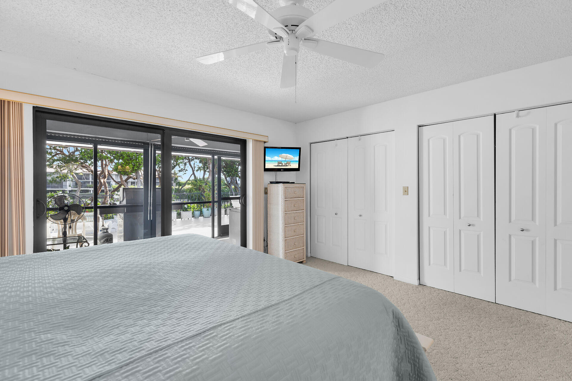 Bedroom with a large bed and sliding glass doors opening to a screened patio.