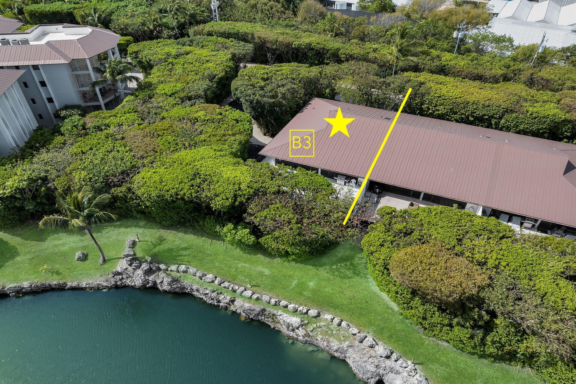 Aerial view of the B3 residence marked on its roof beside a landscaped waterfront shoreline.