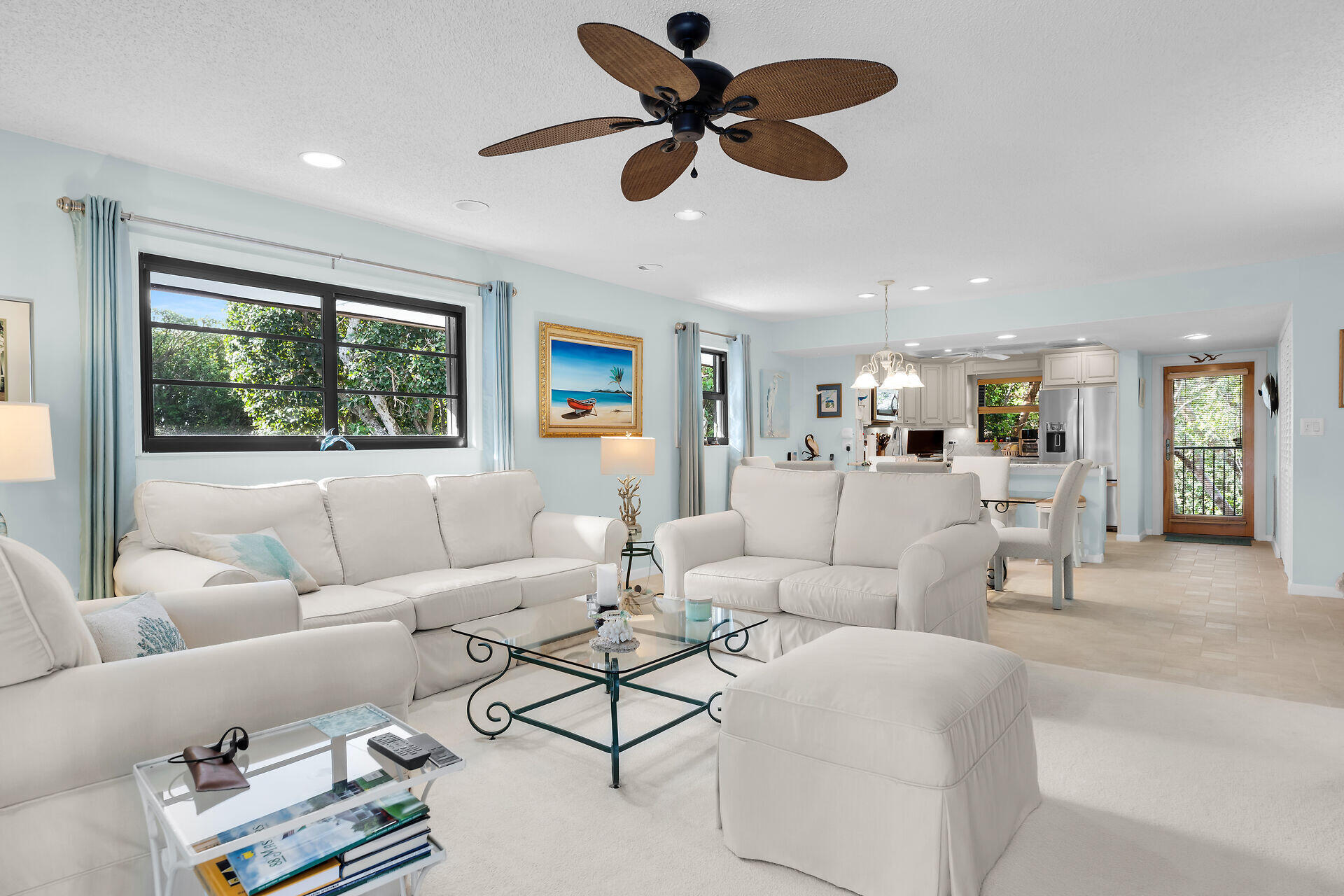 Living room with white sofas, pale blue walls, and an open-plan kitchen and dining area.