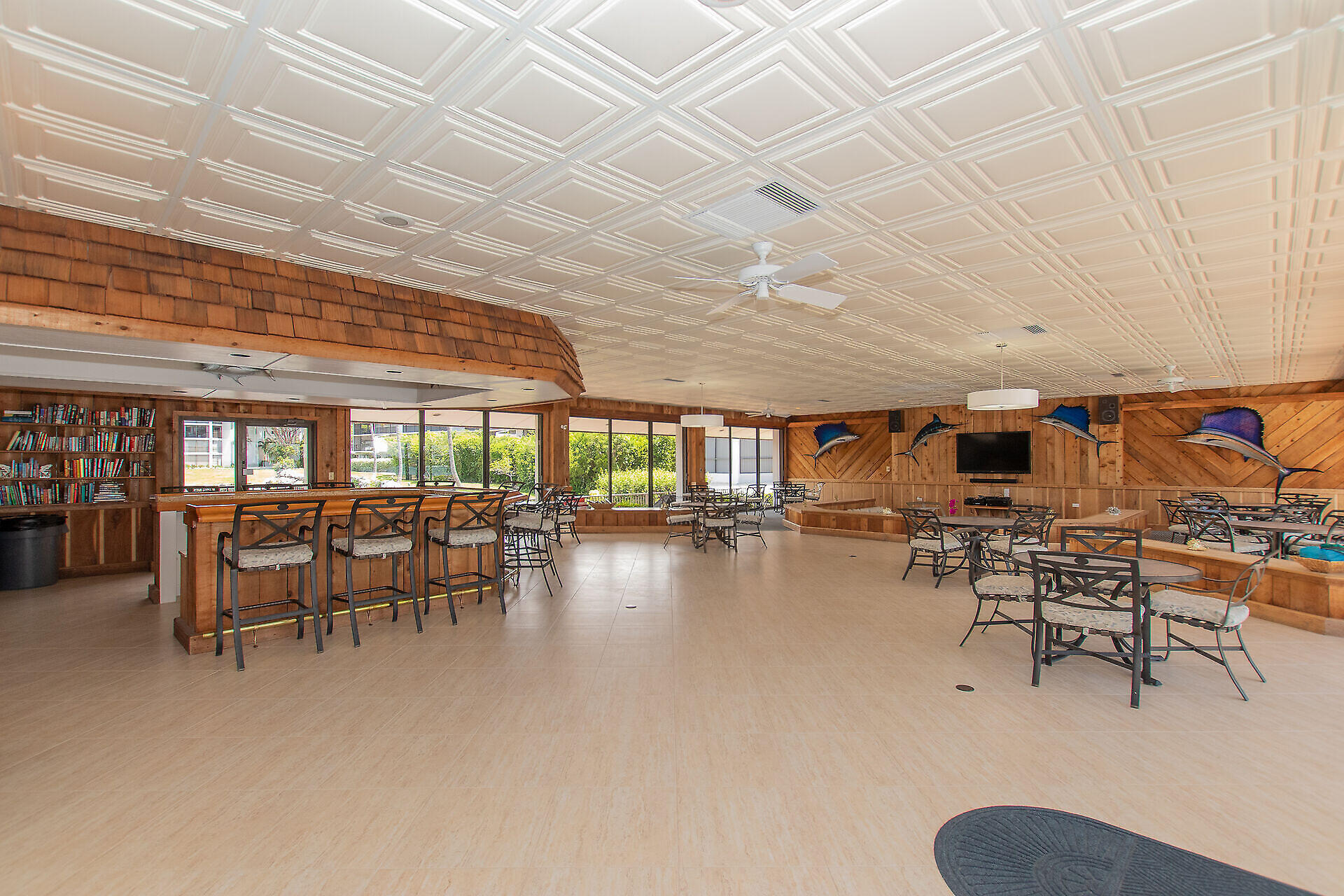 Community lounge with a wood-paneled bar, dining tables, and decorative fish on the walls.