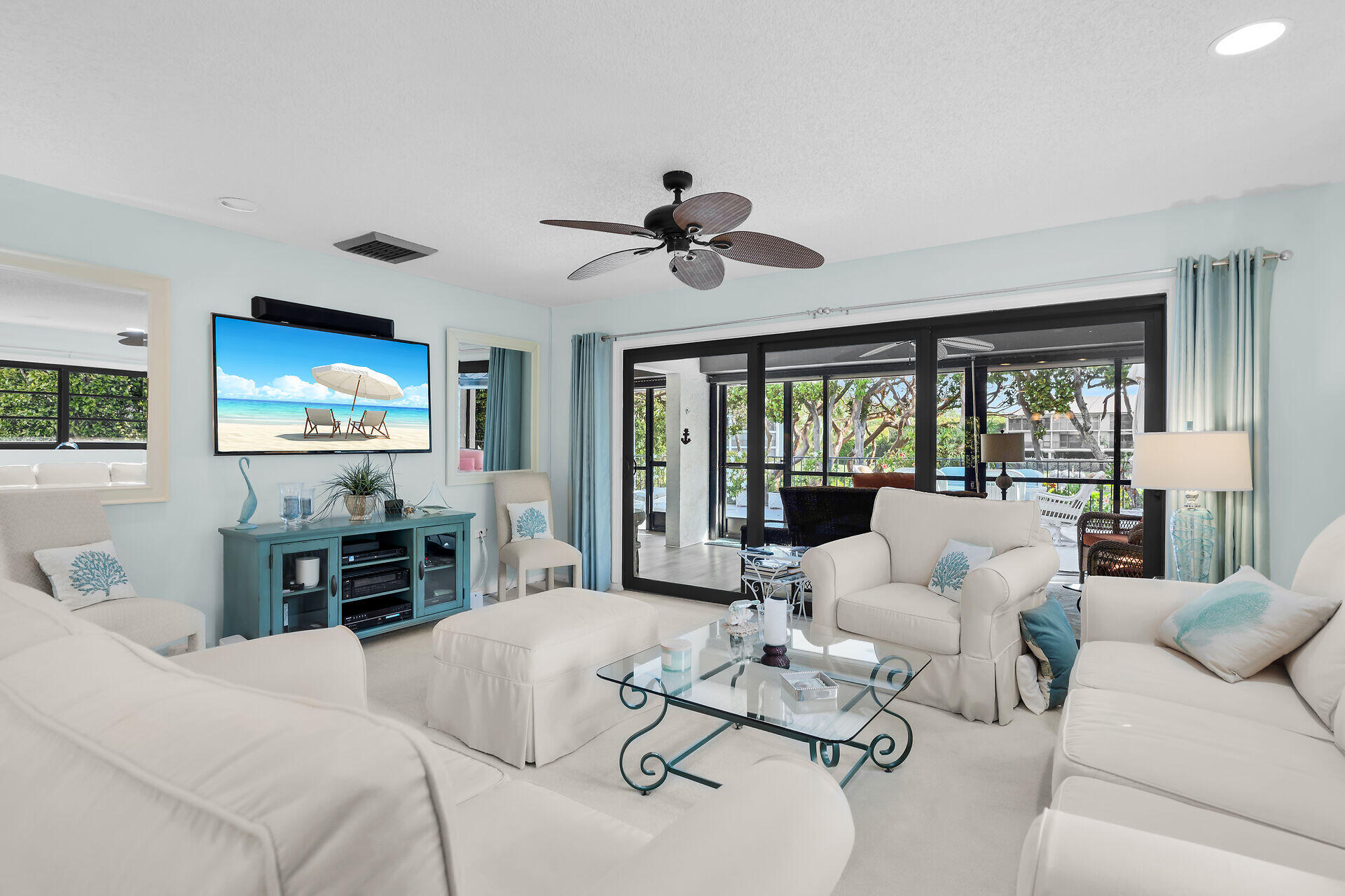 Living room with white seating and sliding glass doors opening to a covered patio.