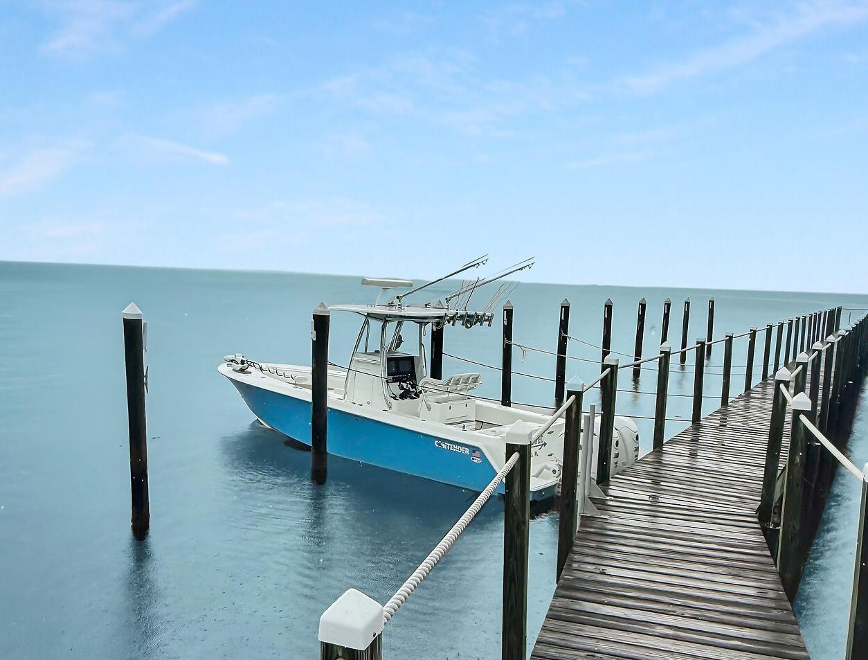 Fishing boat moored beside a long wooden dock over calm turquoise water.
