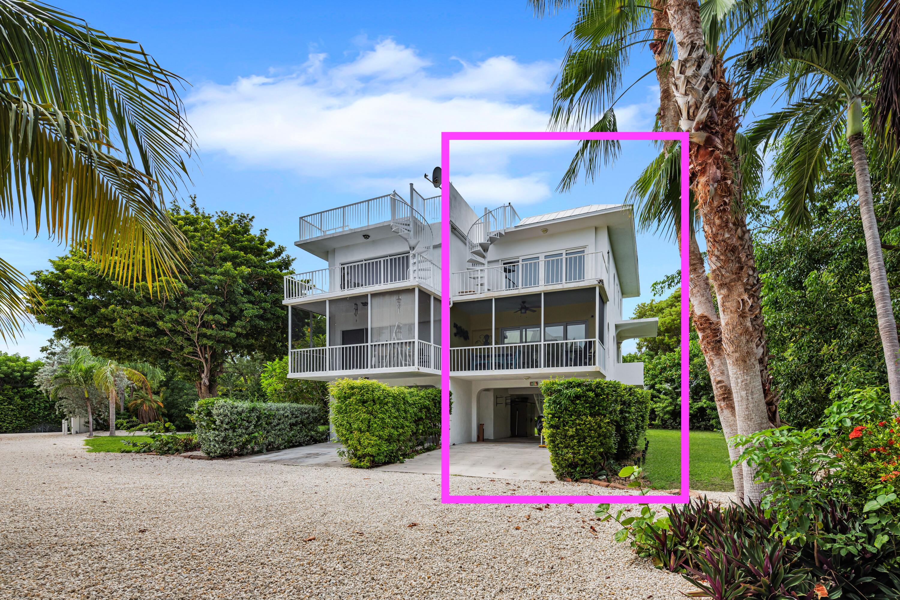 White multi-level house with balconies and rooftop deck, framed by palms and tropical landscaping.