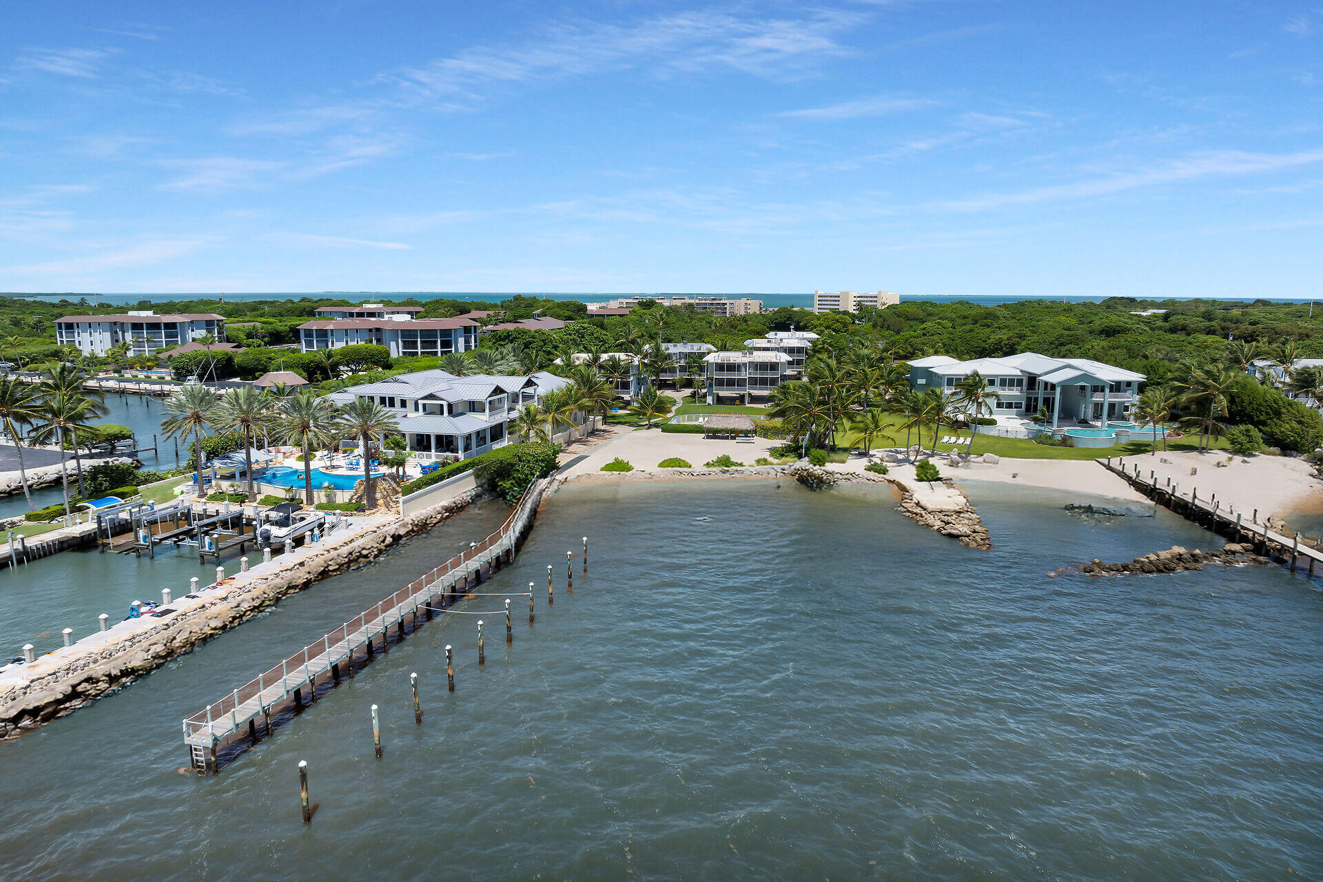 Aerial view of waterfront homes and docks beside canals, with the ocean on the horizon.