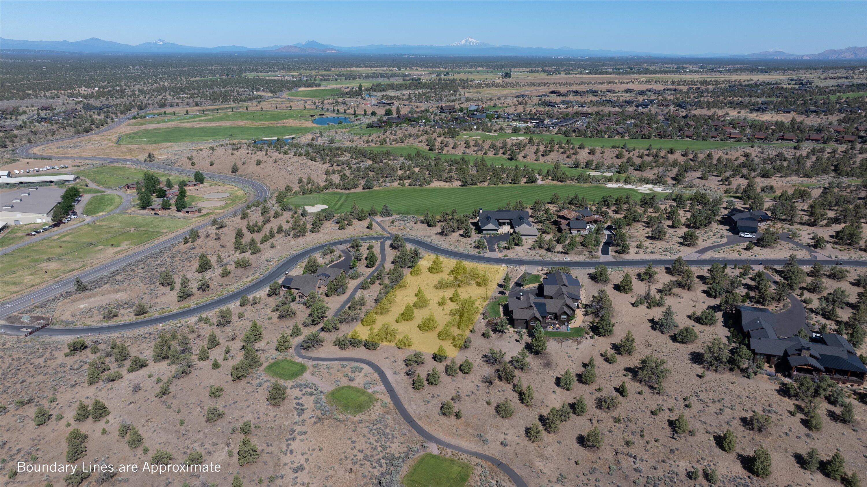 Vacant homesite outlined in yellow, with neighboring homes, golf course, and distant mountains.