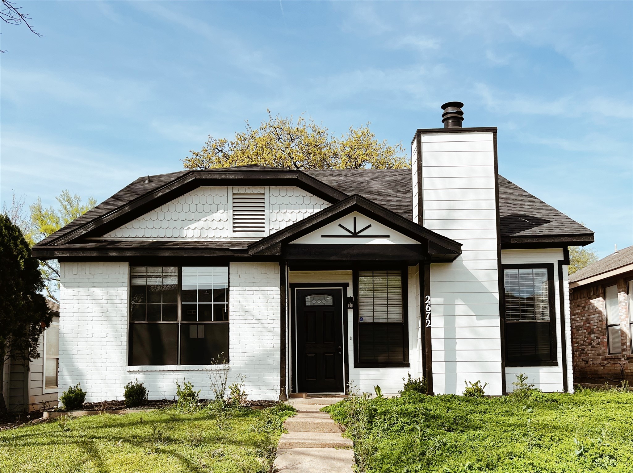 White-brick house with dark trim, a tall chimney, and a walkway leading to the covered entry.