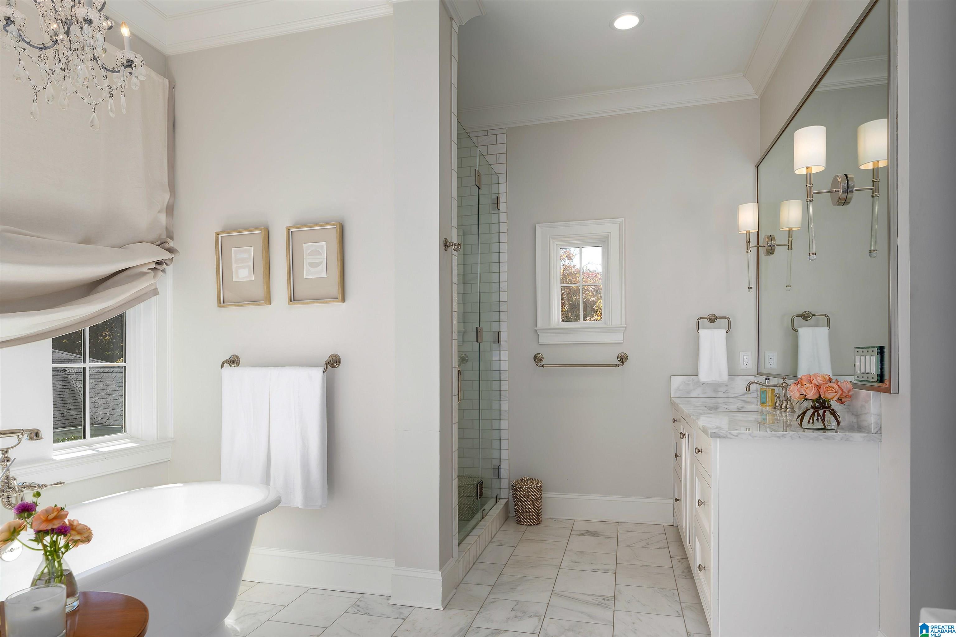 Bright bathroom with a freestanding tub, glass shower, and marble-topped vanity.