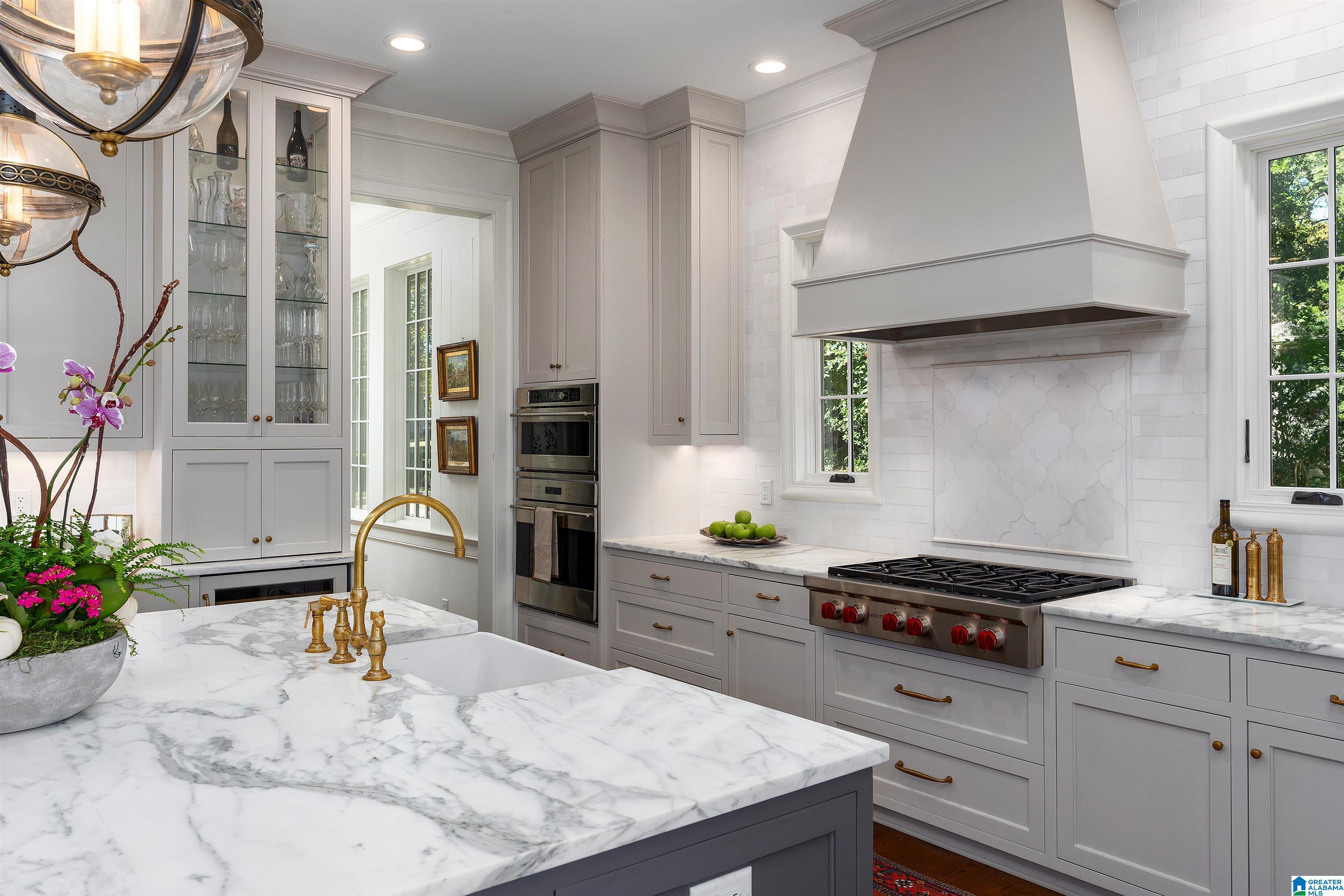 Kitchen with a marble island, gray cabinetry, glass-front cabinets, and a professional gas range.
