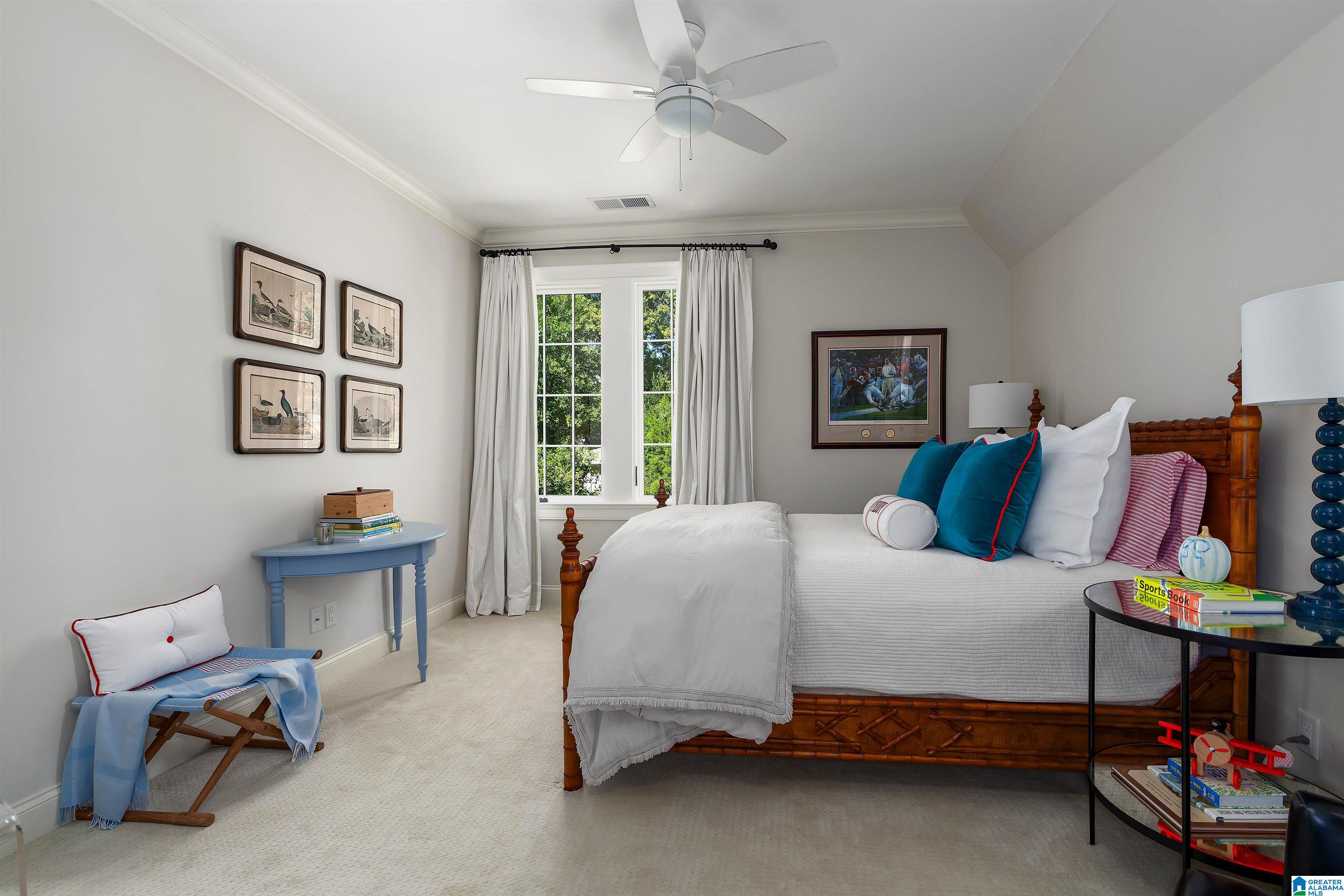 Bedroom with a carved wooden bed, teal pillows, and a curtained window.