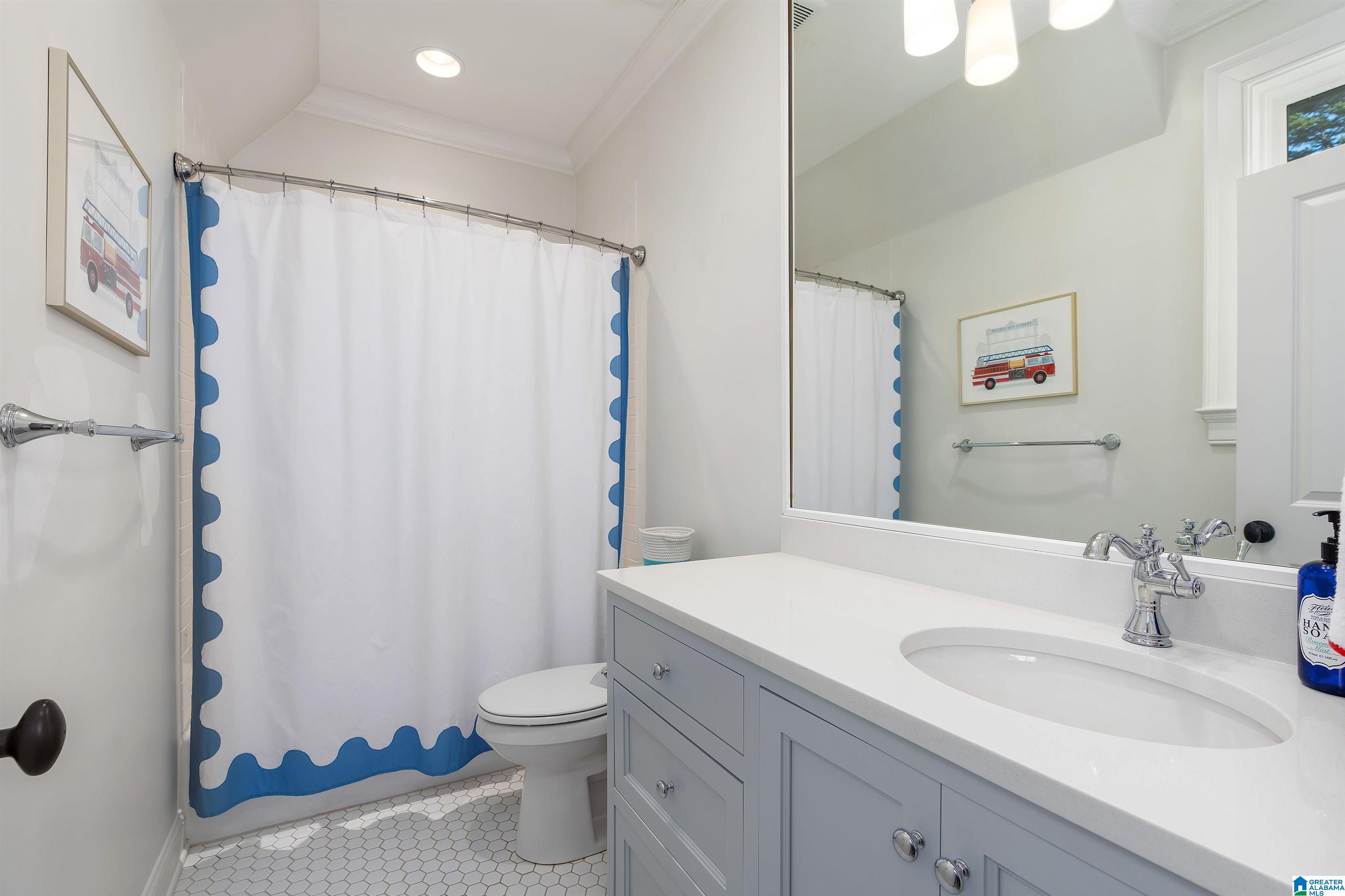 Bathroom with gray vanity, oval sink, and blue-trimmed shower curtain.