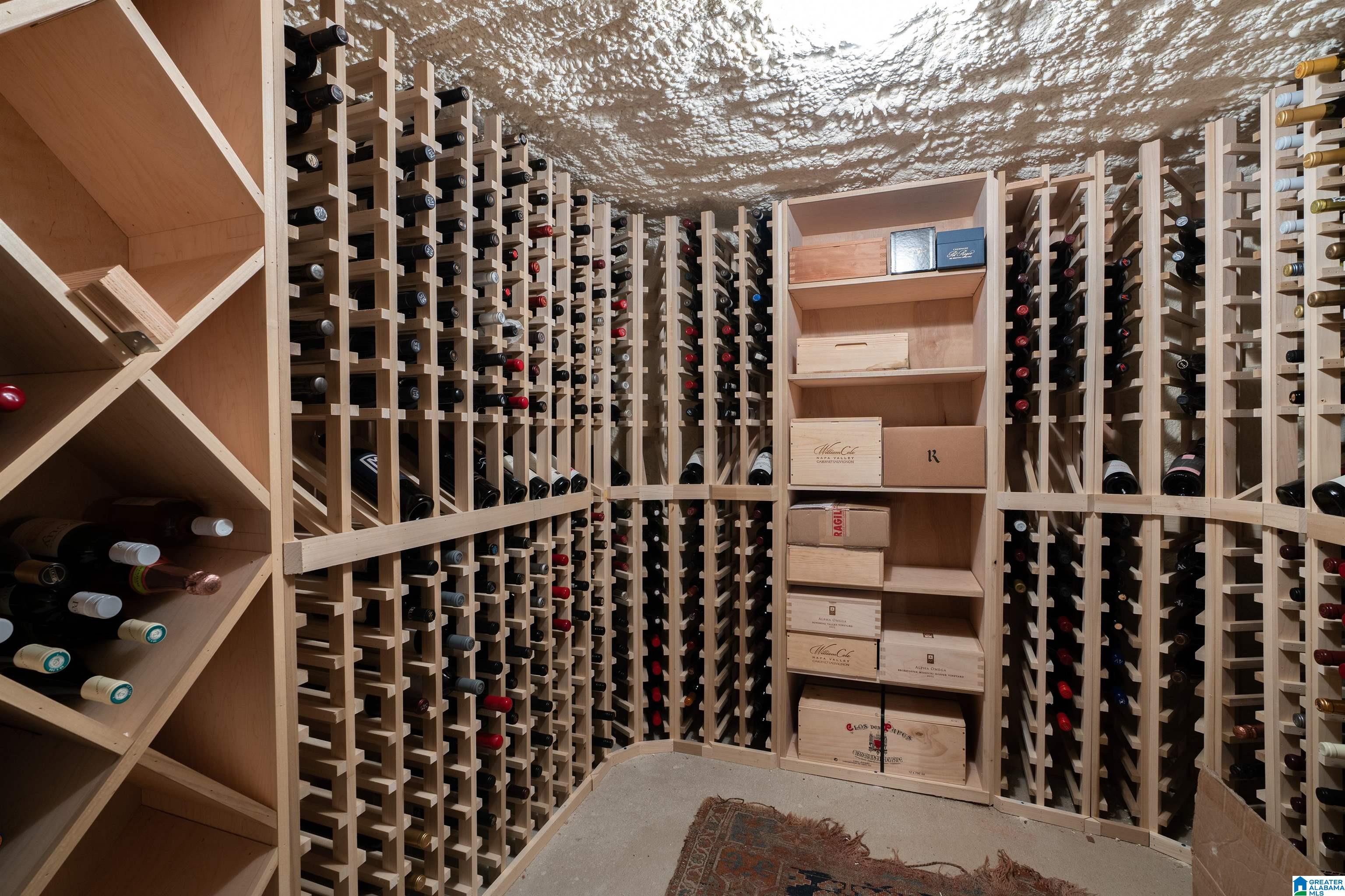 Wine cellar with extensive wooden bottle racks and a central display shelf for wine boxes.
